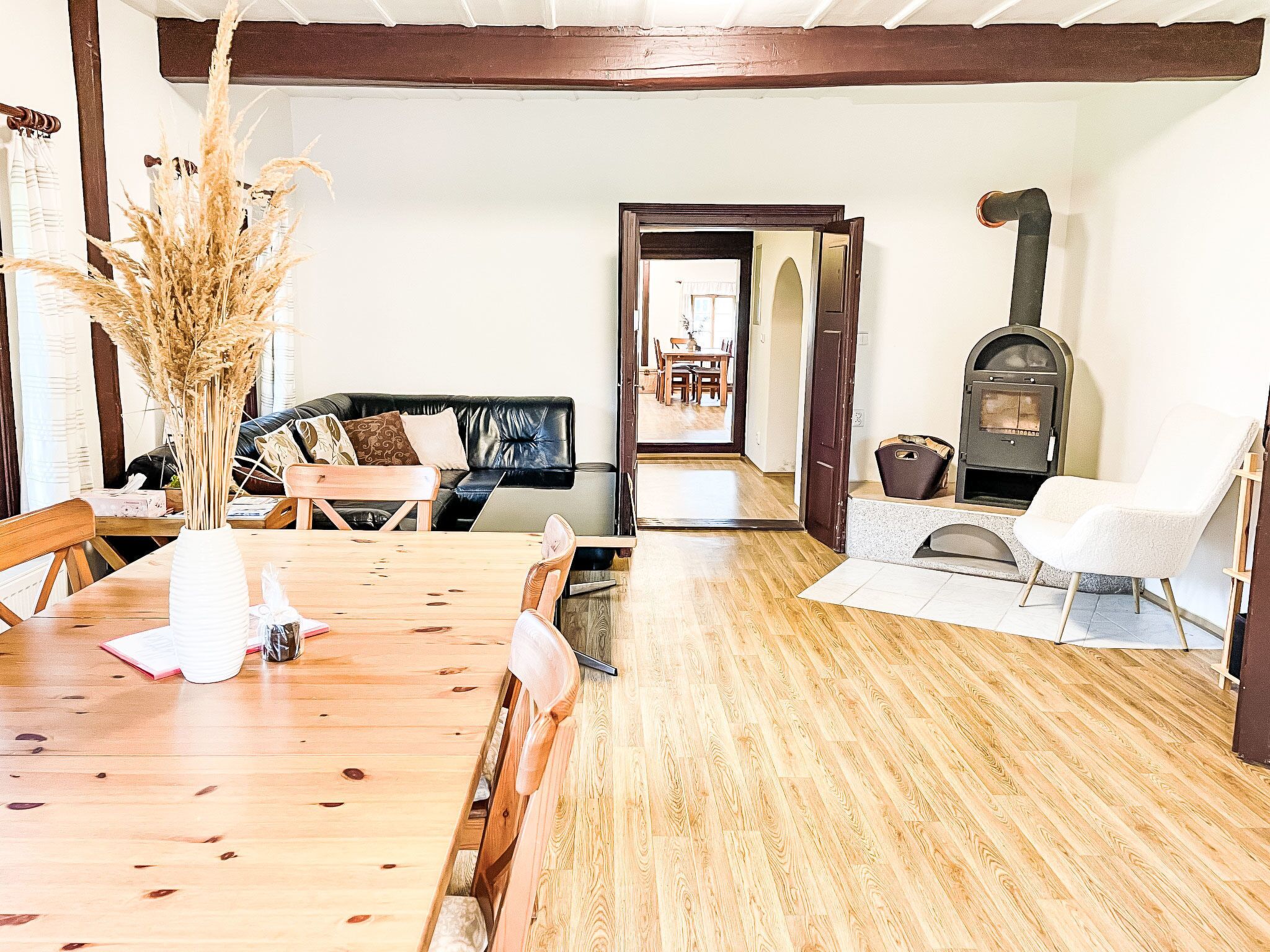 Une table à manger en bois, des chaises, un canapé, une cheminée et une porte donnant sur une autre pièce.