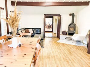 Ein Holzespeisesaal mit Stühlen, ein Sofa, ein Kamin und eine Tür zu einem anderen Raum.