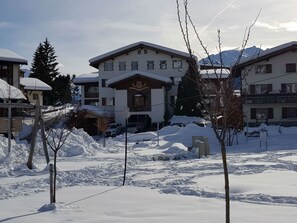 Un edificio cubierto de nieve con una entrada destacada y varias ventanas.