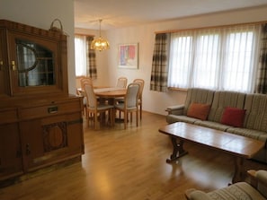 A living room with a sofa, a coffee table, and a dining area with a table and chairs. - Casa Davos Cuort Good, Vella, (Vella), 44004B by Interhome (Vella)