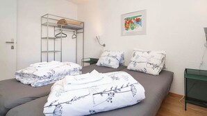A bedroom with a bed, a wardrobe, a framed picture, and a green metal shelf. - Casa Fulin, Obersaxen Affeier, (Obersaxen Affeier), 34075B by Interhome (Obersaxen Affeier)