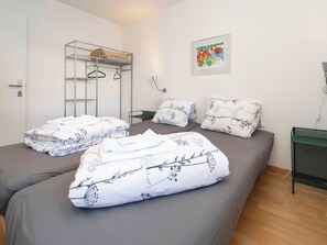 Ein Schlafzimmer mit einem Bett, einem Kleiderschrank, einem gerahmten Bild und einem grünen Metallregal.