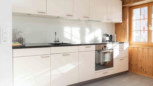 A modern kitchen with white cabinetry, a stainless steel sink, and a built-in oven. - Casa Fulin, Obersaxen Affeier, (Obersaxen Affeier), 34075B by Interhome (Obersaxen Affeier)