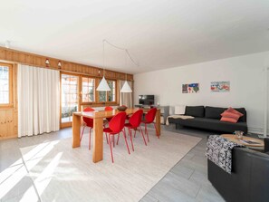 Ein modernes Wohnzimmer mit Essbereich, einer Couch und einem Fernseher.