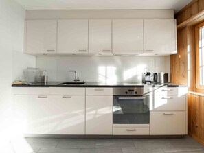 Eine moderne Küche mit weißen Schränken, einer schwarzen Arbeitsplatte und einem eingebauten Backofen.