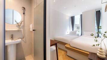 Una habitación de hotel moderna con baño, una cama, una mesita de noche y vistas a la ciudad.