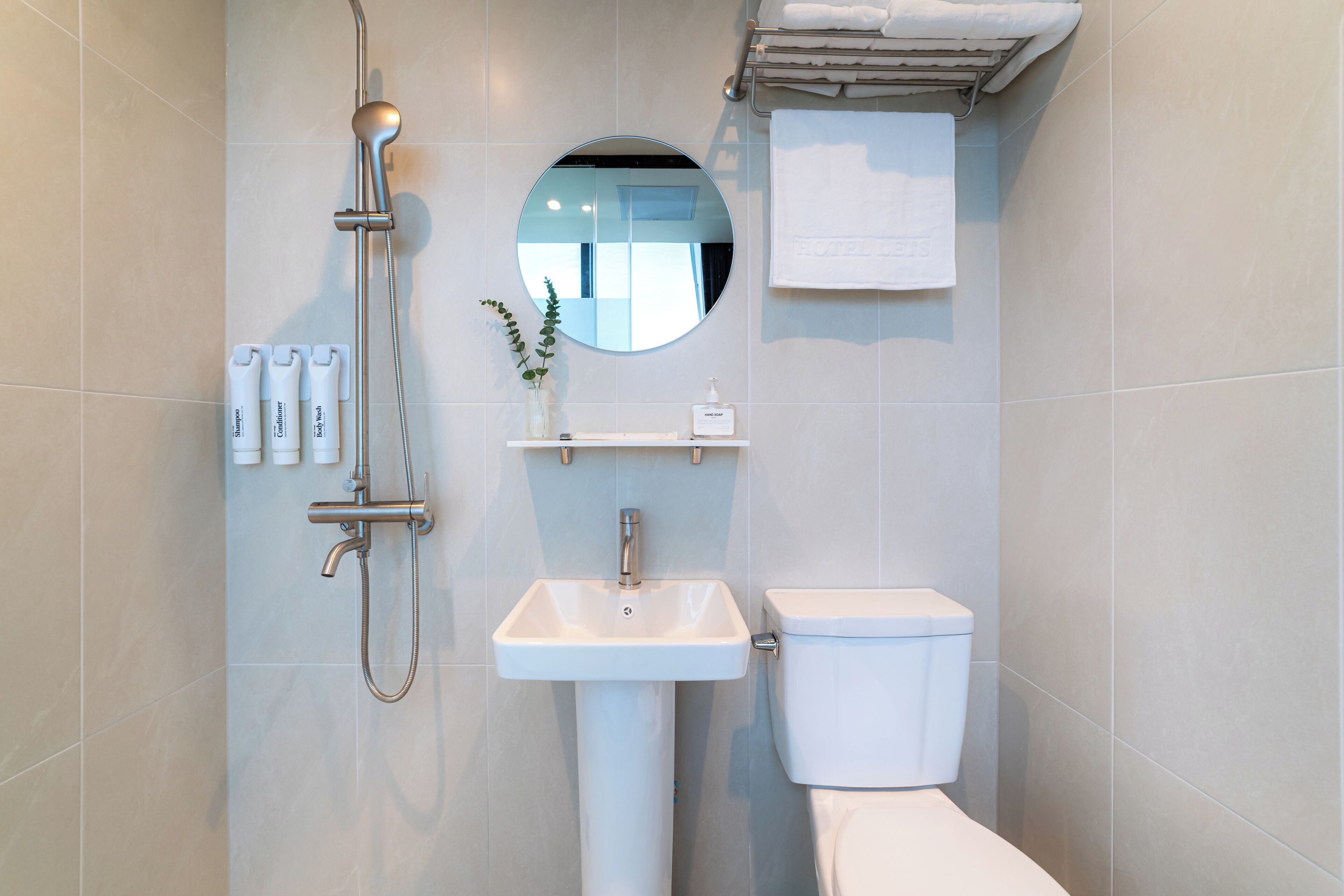 A modern bathroom with a shower, sink, toilet, and a mirror.