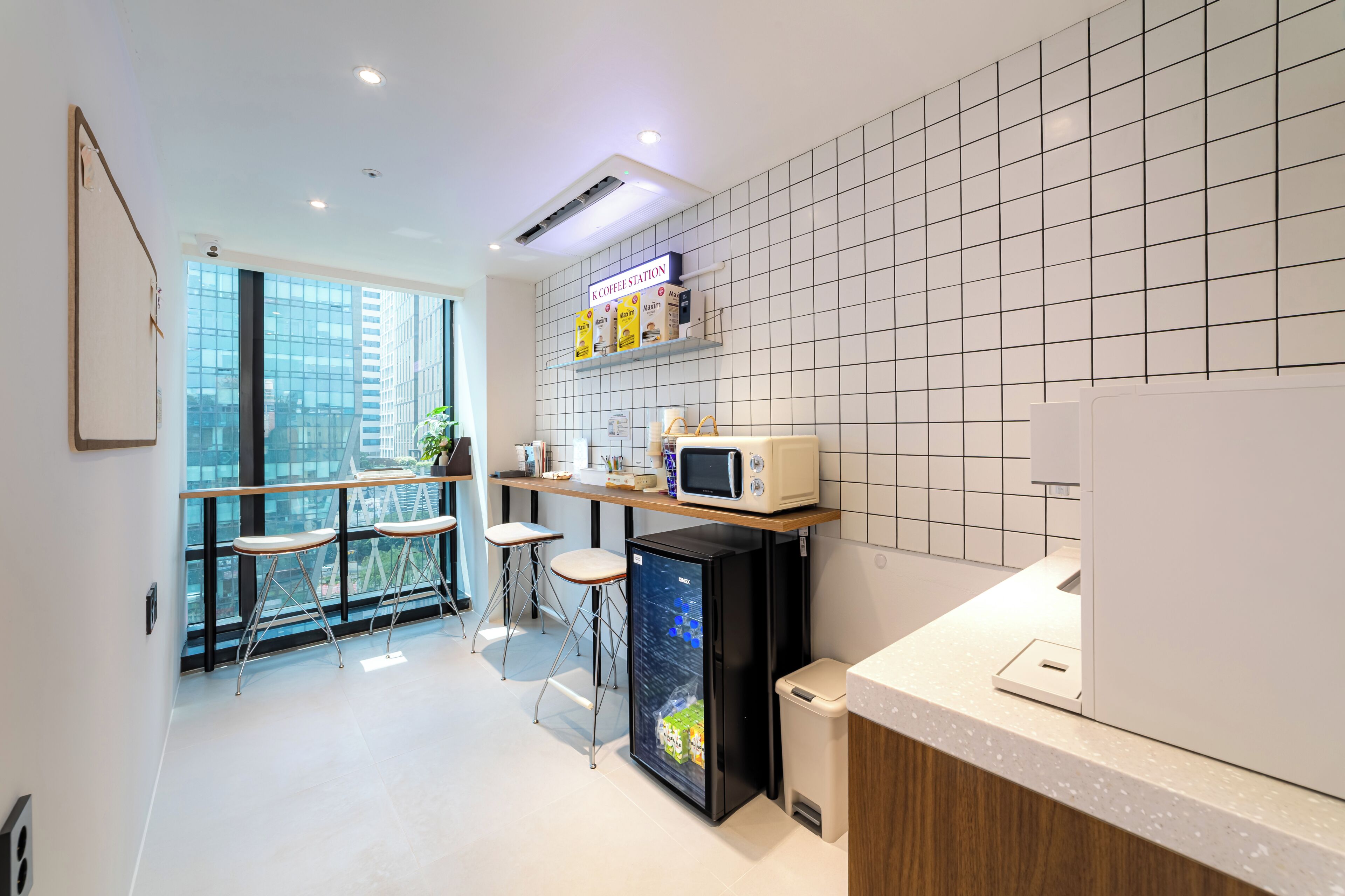 A modern kitchen with a refrigerator, microwave, and coffee station.