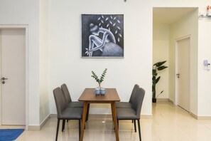 Una habitación con una mesa de comedor, dos sillas, un cuadro en la pared y una planta en maceta.