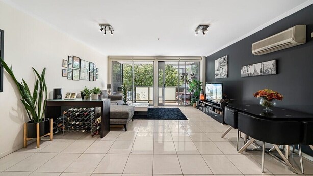 A modern living room with a sofa, a coffee table, a black console table, and a large window. - Light-filled, spacious 2 bdrm Prahran apartment with free parking. (Prahran)