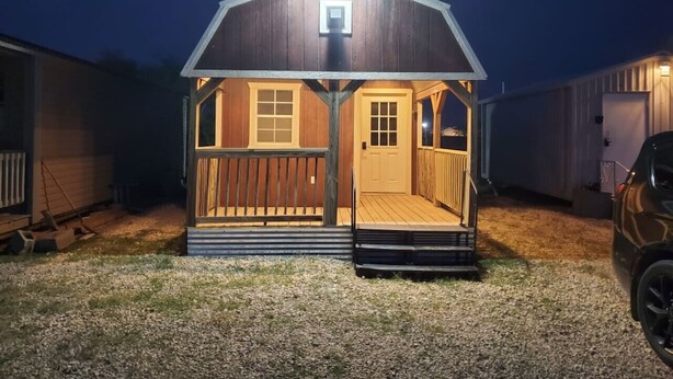 A small, single-story wooden structure with a porch, a door, and a window.