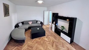 A modern living room with a grey sectional sofa, a black coffee table, and a built-in TV unit.