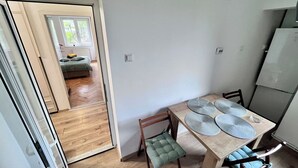 A dining area with a wooden table, chairs, and a view of a bedroom through an open door.
