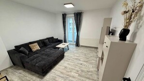 Un salon moderne avec un canapé gris foncé, une petite table blanche et un meuble blanc.