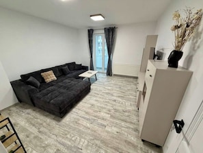 Un salon moderne avec un canapé gris foncé, une petite table blanche et un meuble blanc.