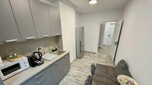 Une cuisine moderne avec des meubles gris, un four à micro-ondes, une bouilloire et un coin repas comprenant une table et des chaises.