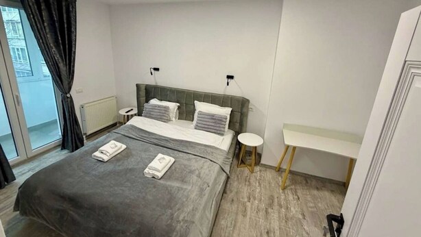 Une chambre moderne avec un grand lit, des tables de chevet et une vue sur l’extérieur.