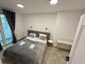 Un dormitorio moderno con una cama grande, mesitas de noche y vistas al exterior.