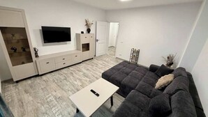 Un salon moderne comprenant un canapé, une table basse, un téléviseur et un meuble.