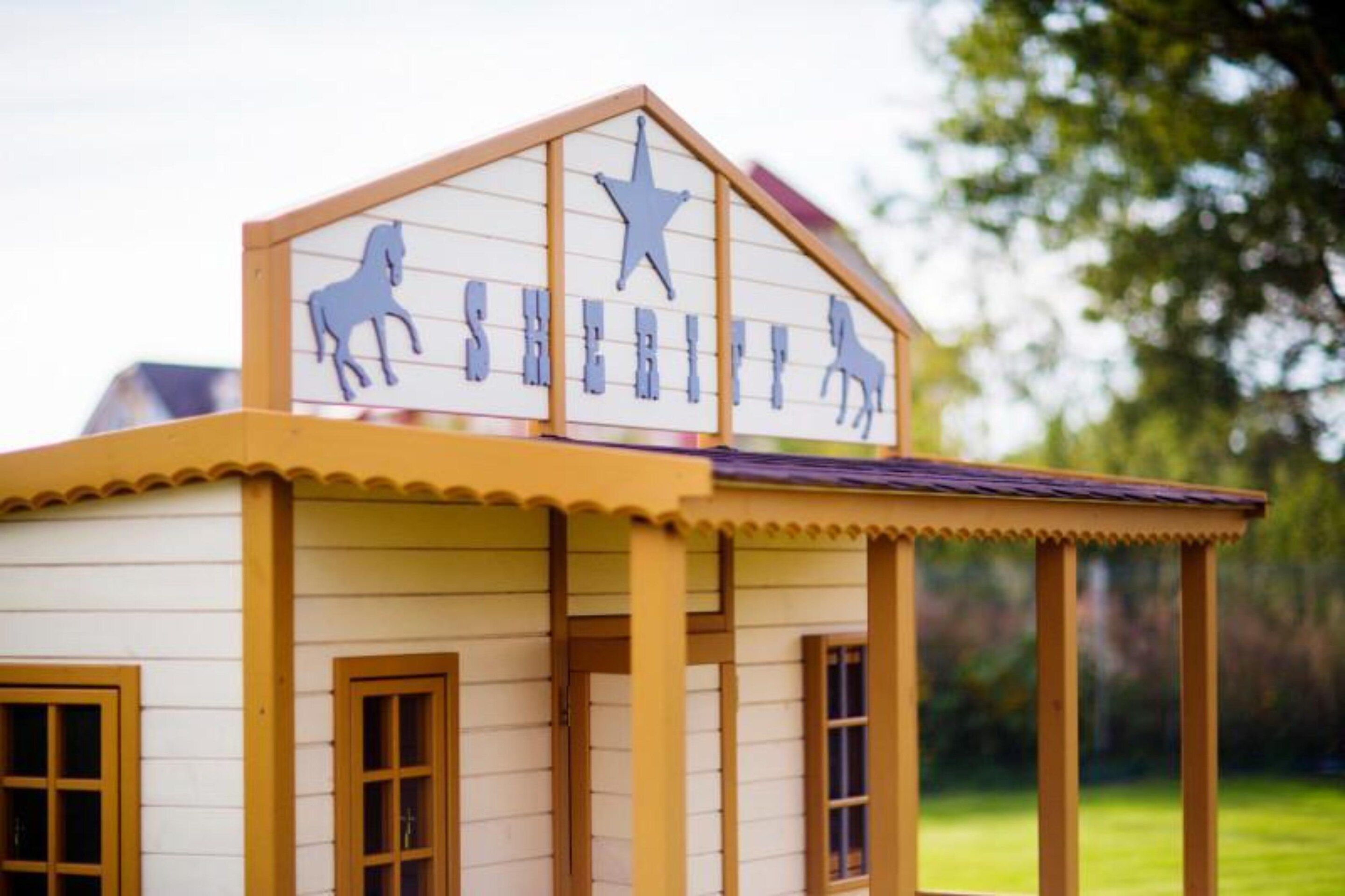 Een model van een sheriffskantoor, met een ster op het dak en silhouetten van paarden aan de muur.