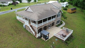 A two-story house with a covered patio, a front porch, and a stone facade. - Lakefront Retreat with private dock, game room, bar, and sunroom views (Cadiz)