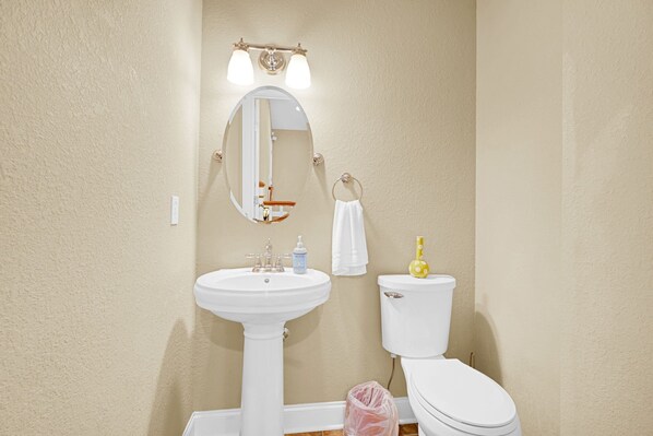 A bathroom with a white sink, a toilet, a mirror, and a towel ring.