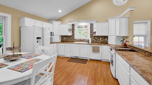 A kitchen with white cabinets, a granite countertop, a clock, and a window. - Lakefront Retreat with private dock, game room, bar, and sunroom views (Cadiz)
