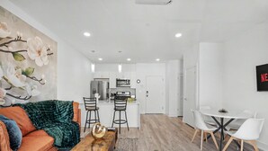 A modern living room with a sofa, coffee table, and a dining area with chairs and a table. - Bright 1BD Sleeps 2 Near Liberty Bell Center City (Philadelphia)