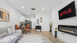 A modern living room with a sofa, coffee table, and a fireplace. A kitchen is visible in the background. - Chic 1BD Sleeps 2 Near Independence Hall Philly (Philadelphia)