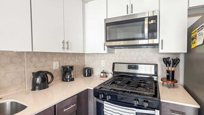 Cocina moderna con electrodomésticos de acero inoxidable, incluyendo un microondas, estufa y cafetera.