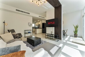 A modern living room with a sofa, coffee table, and a flat-screen TV mounted on the wall.