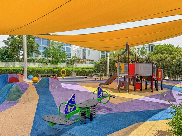 A playground with colorful play structures and a shaded area.