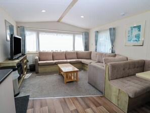 Uma sala de estar com sofá seccional, televisão e mesa de centro de madeira.