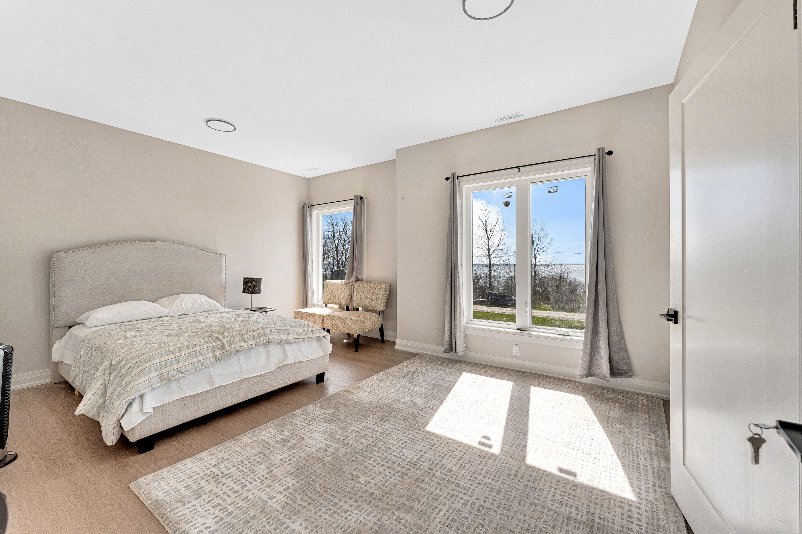 Ein Schlafzimmer mit einem Bett, einem Sessel, einem Fenster und einer Tür.