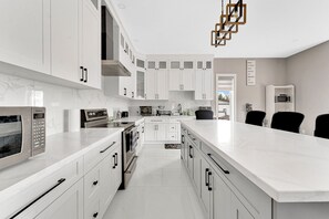 A modern kitchen with white cabinets, stainless steel appliances, and a marble countertop. - Chattage: Lake Erie Luxury Estate w/ Hot Tub And EV  charger (Wheatley)