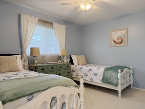 A bedroom with two beds, a nightstand, a dresser, a ceiling fan, and a framed picture on the wall. - Fiddler’s Green 2BR Getaway (Englewood)