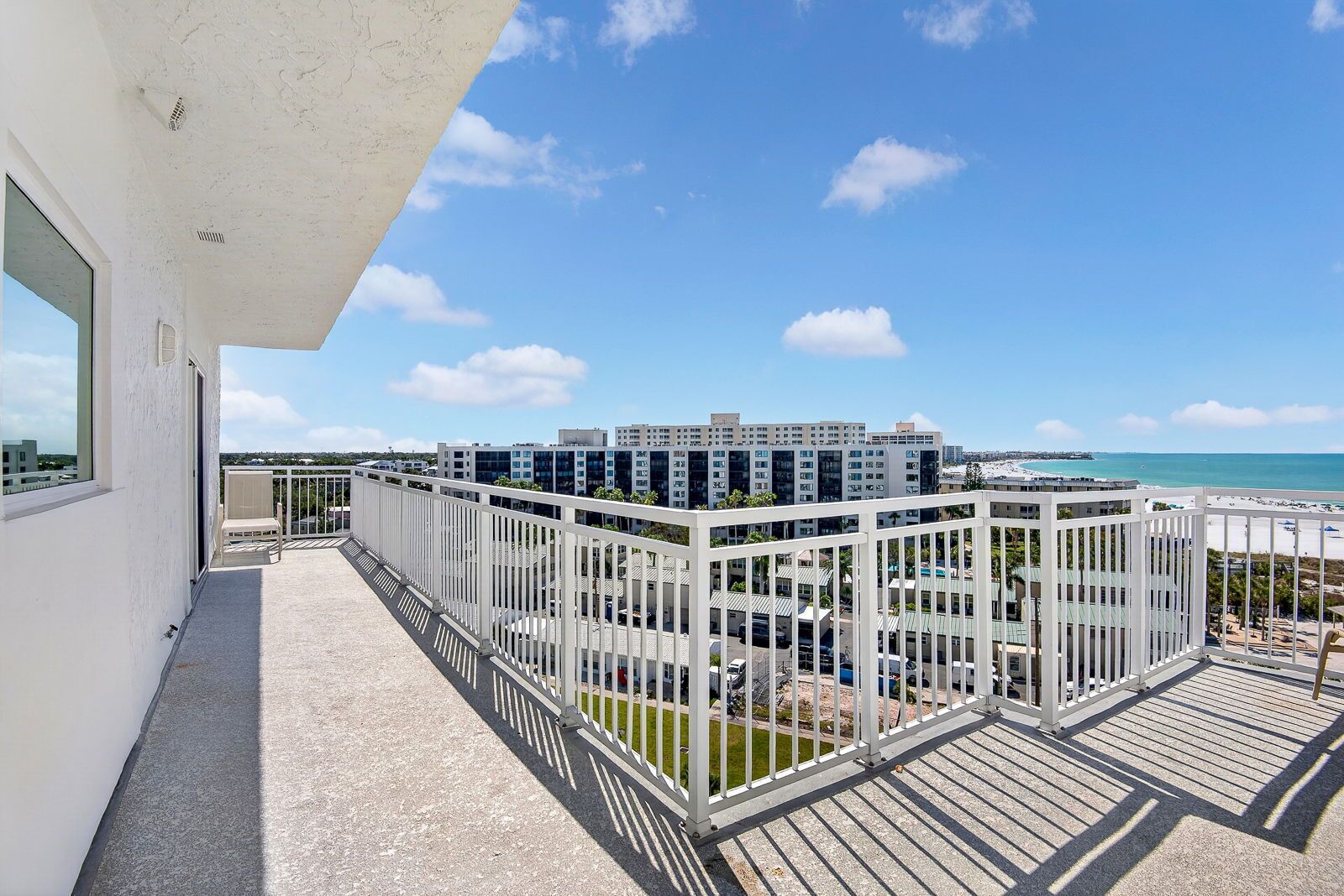 Ein Balkon mit Blick auf einen modernen Gebäudekomplex und das Meer.