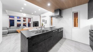 A modern kitchen with a large island, built-in appliances, and a wooden ceiling. - THE POLARIS (Sapporo)