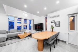 Una sala de estar moderna con sofá, mesa de centro, mesa de comedor y televisor.