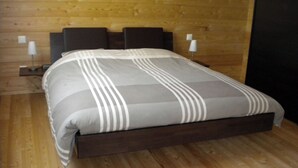 A bed with a striped bedspread, wooden headboard, and bedside lamps. - Bevernage, (Splügen), by Interhome (Splügen)