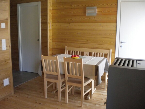 Ein Zimmer mit Holzwänden, einem Tisch, Stühlen, einer Tür und einem kleinen Wandobjekt.
