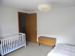 Ein Schlafzimmer mit einem Kinderbett, einer Holzkommode und einem Kleiderschrank.