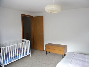 A room with a crib, a wooden dresser, and a door. - Haus Wanner, (Splügen), by Interhome (Splügen)