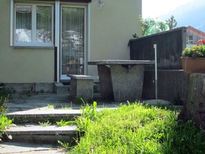 A concrete bench and table in a garden area with steps leading up to a door. - Haus Wanner, (Splügen), by Interhome (Splügen)