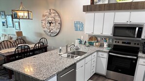 Eine moderne Küche mit Granit-Arbeitsplatten, Edelstahlgeräten und einem Essbereich mit Holzsesseln.