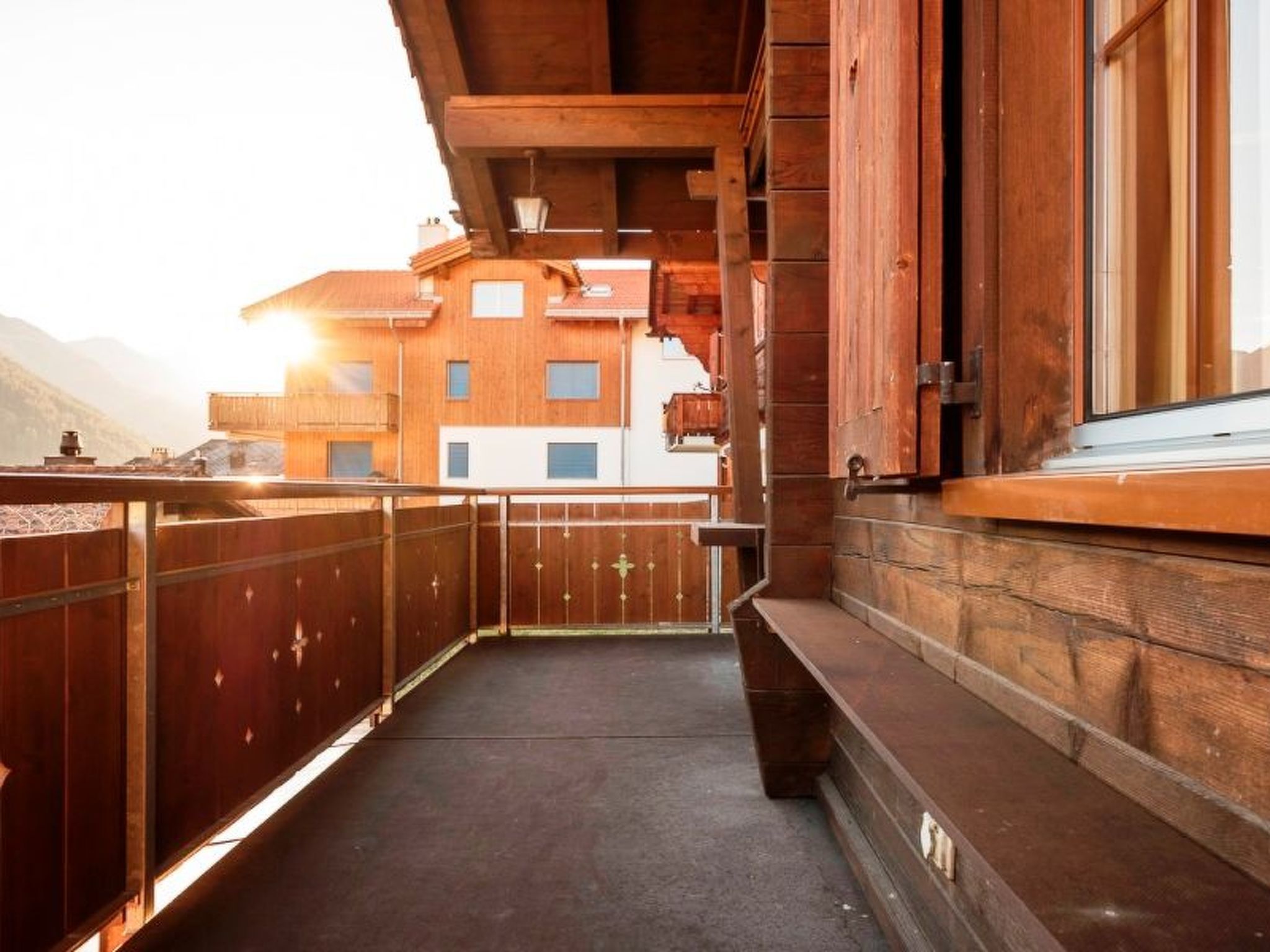 A wooden balcony with a view of a mountain and a building.