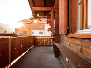 Ein Holzbalkon mit Blick auf einen Berg und ein Gebäude.