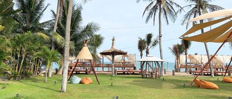 A tropical resort with palm trees, outdoor seating, and a view of the sea.