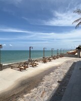 A beachside walkway with lounge chairs and a wooden boat.