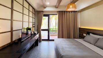A hotel room with a bed, a desk with a computer, a lamp, and a view of the outdoors.